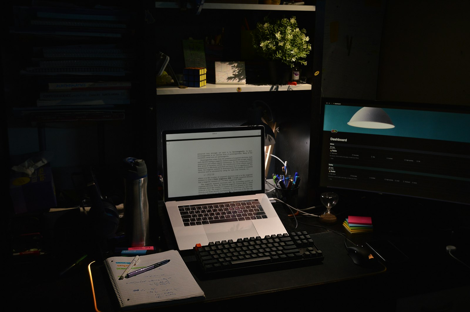 A laptop open on a desk in a dim, focused room